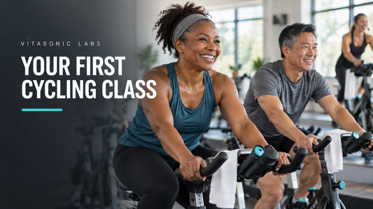 Vitasonic Labs cycling banner showing two smiling adults riding seated on stationary bikes in a bright class studio.